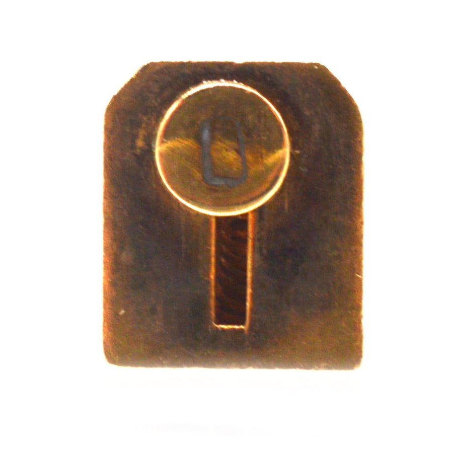 Miniature brass key with a circular top and rectangular body, showcasing intricate craftsmanship.