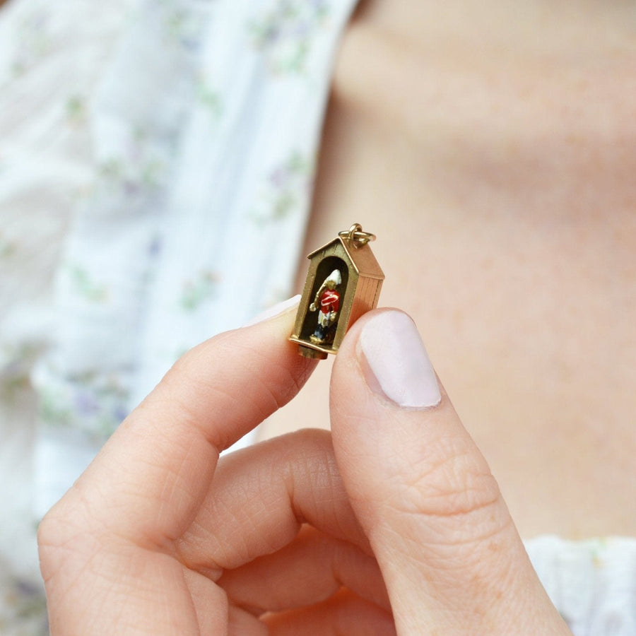 Miniature Queen's Life Guard charm in a sentry box held by a hand, showcasing exquisite gold and enamel design.