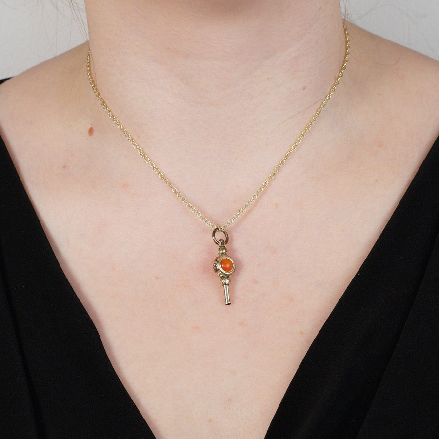 Gold cased watch key pendant featuring carnelian and white chalcedony on a model's neck.