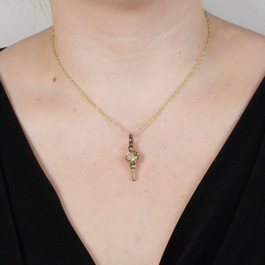 Regency gold cased watch key pendant with carnelian and white chalcedony on a gold chain, worn elegantly.
