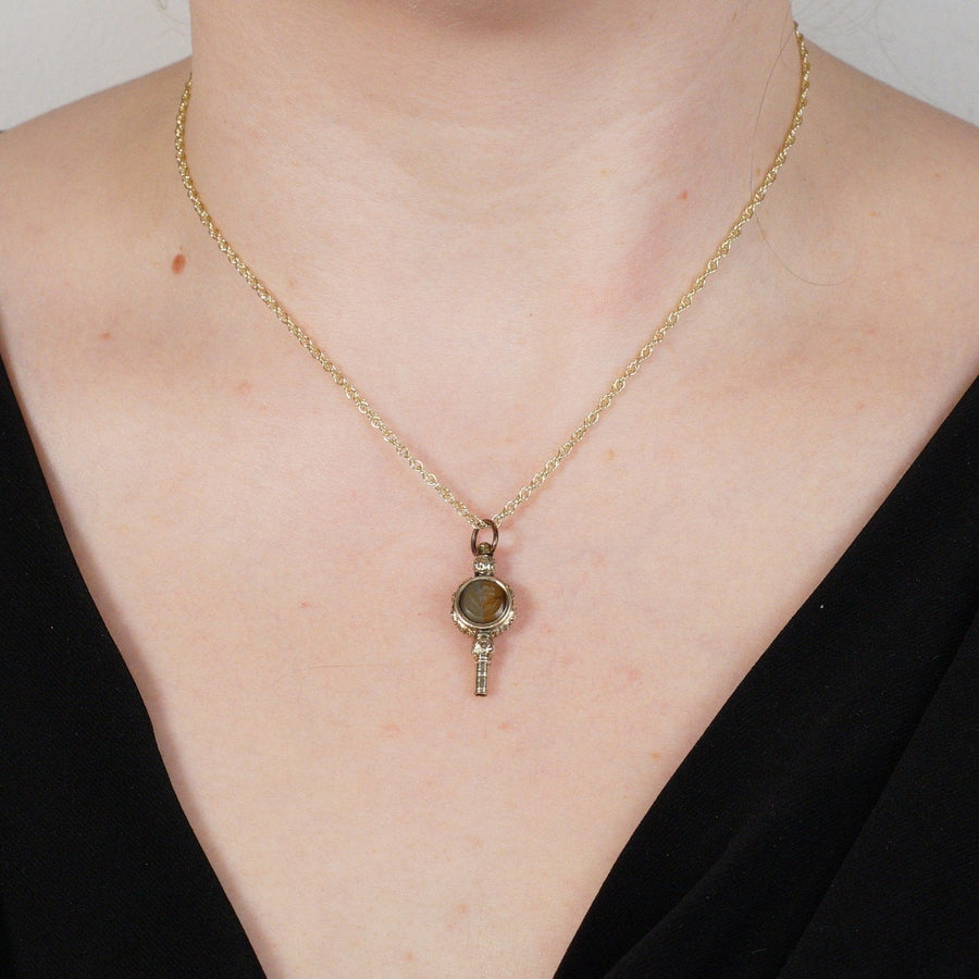 Regency gold cased watch key pendant with onyx and agate, featuring rose intaglio design worn on a chain.