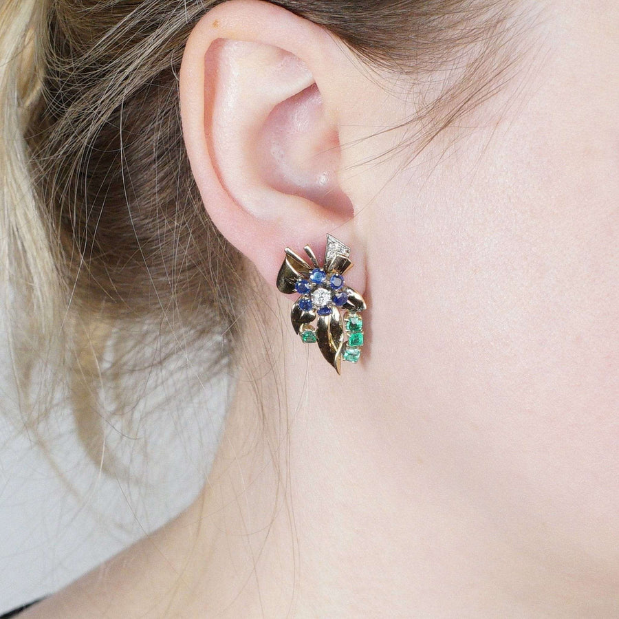 Retro 1940s 18ct gold earrings featuring vibrant emerald, diamond, and sapphire gemstones in a floral design.