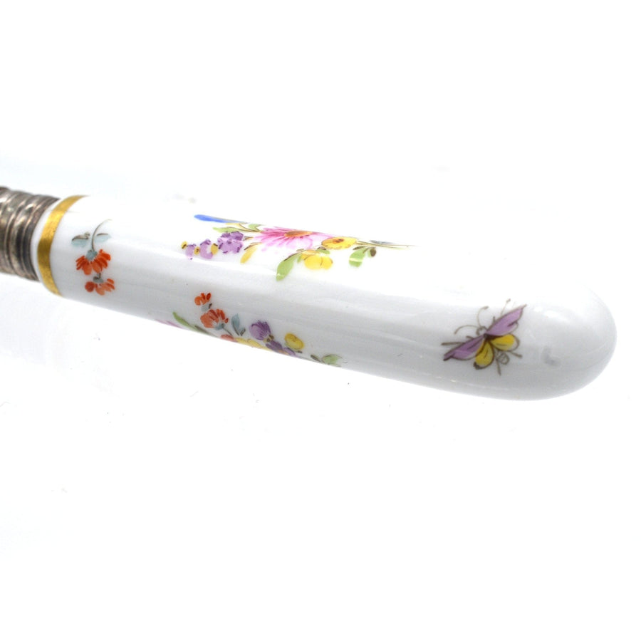 Close-up of a painted Meissen porcelain handle on Thomas Goode silver cutlery featuring floral designs.