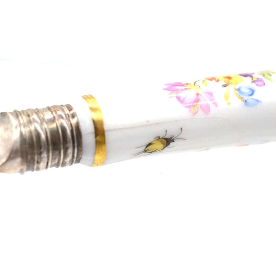 Close-up of a porcelain cutlery handle featuring floral designs and a yellow bee illustration.