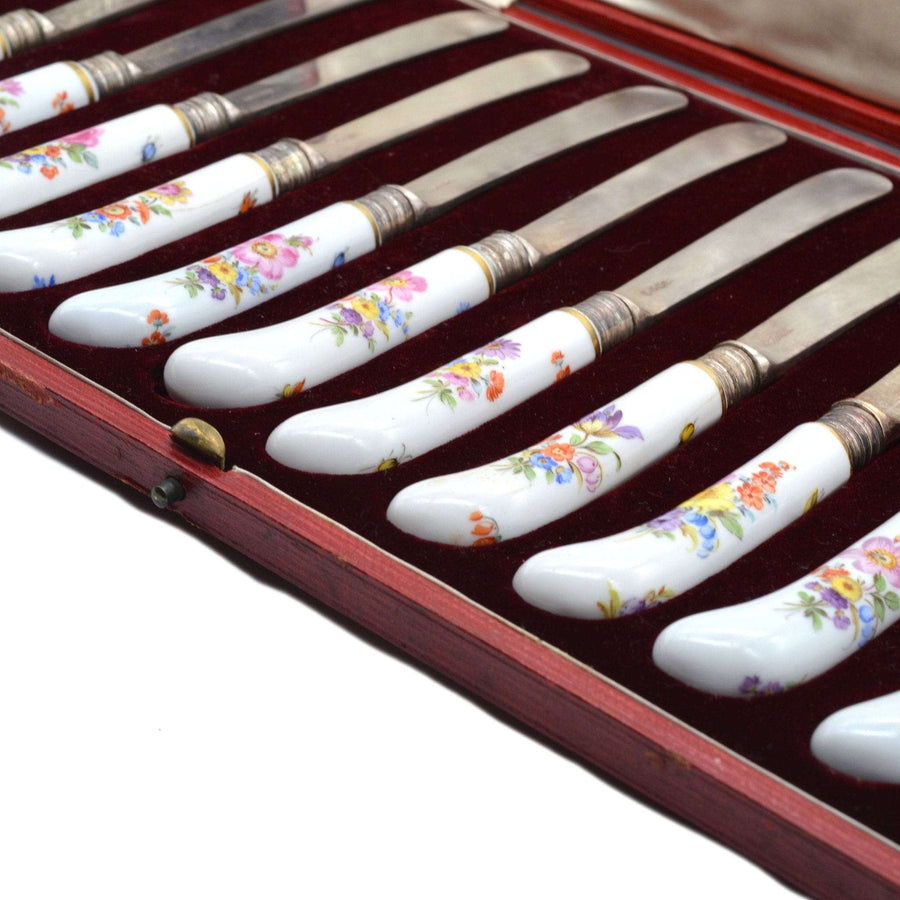 Set of 12 late 19th century Thomas Goode silver knives with painted Meissen porcelain handles in red leather case.
