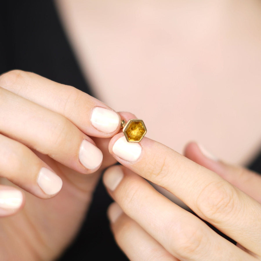 Hand holding a tiny early Victorian 9ct gold hexagonal citrine seal with an intaglio of a dog.