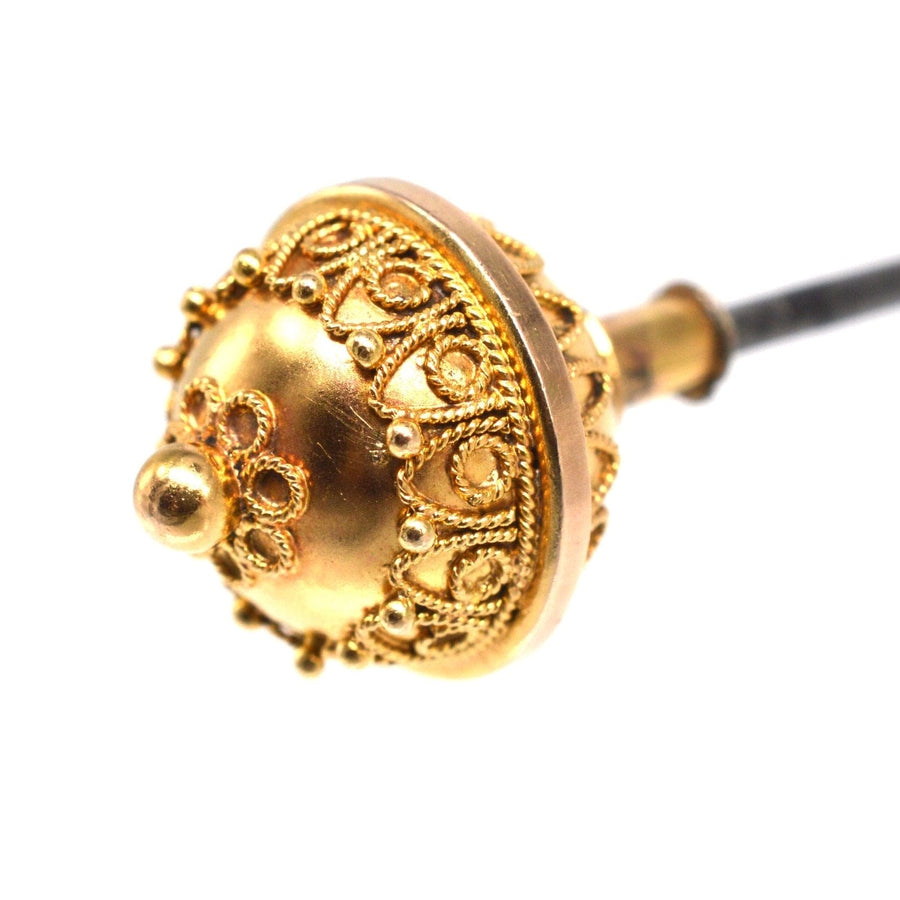 Close-up of a Victorian 15ct gold Etruscan ball hat pin with ornate detailing and decorative scrolls.