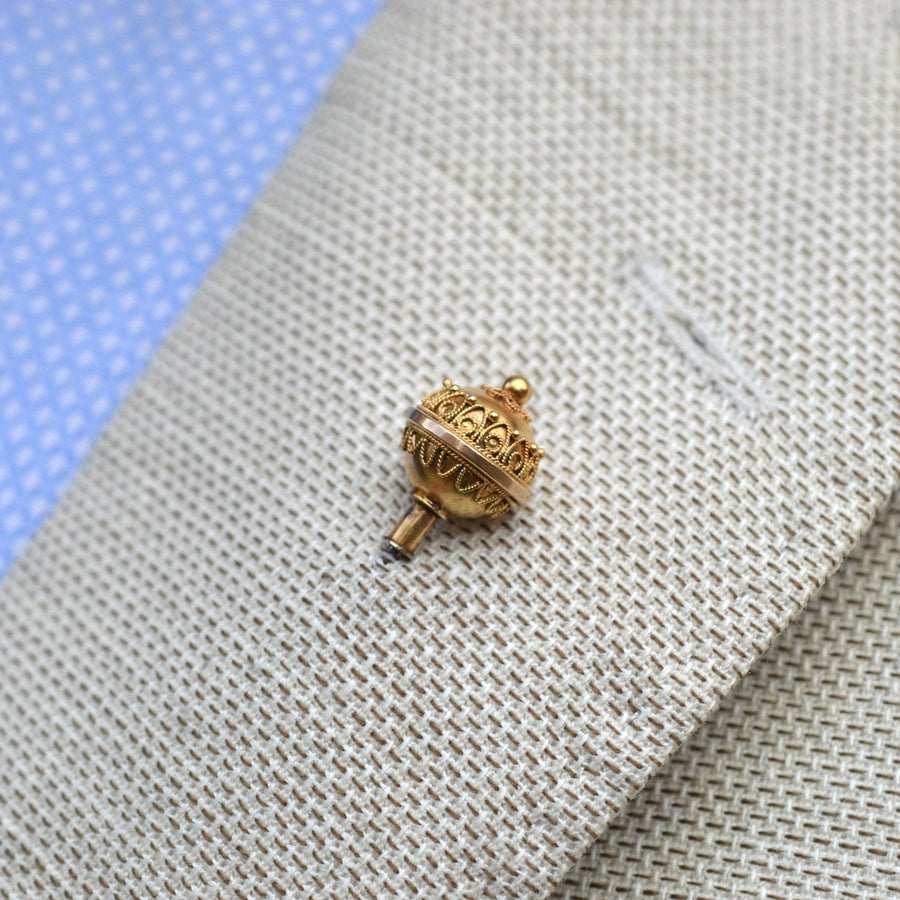 Victorian 15ct gold Etruscan ball hat pin on a textured blazer, showcasing intricate scroll details.