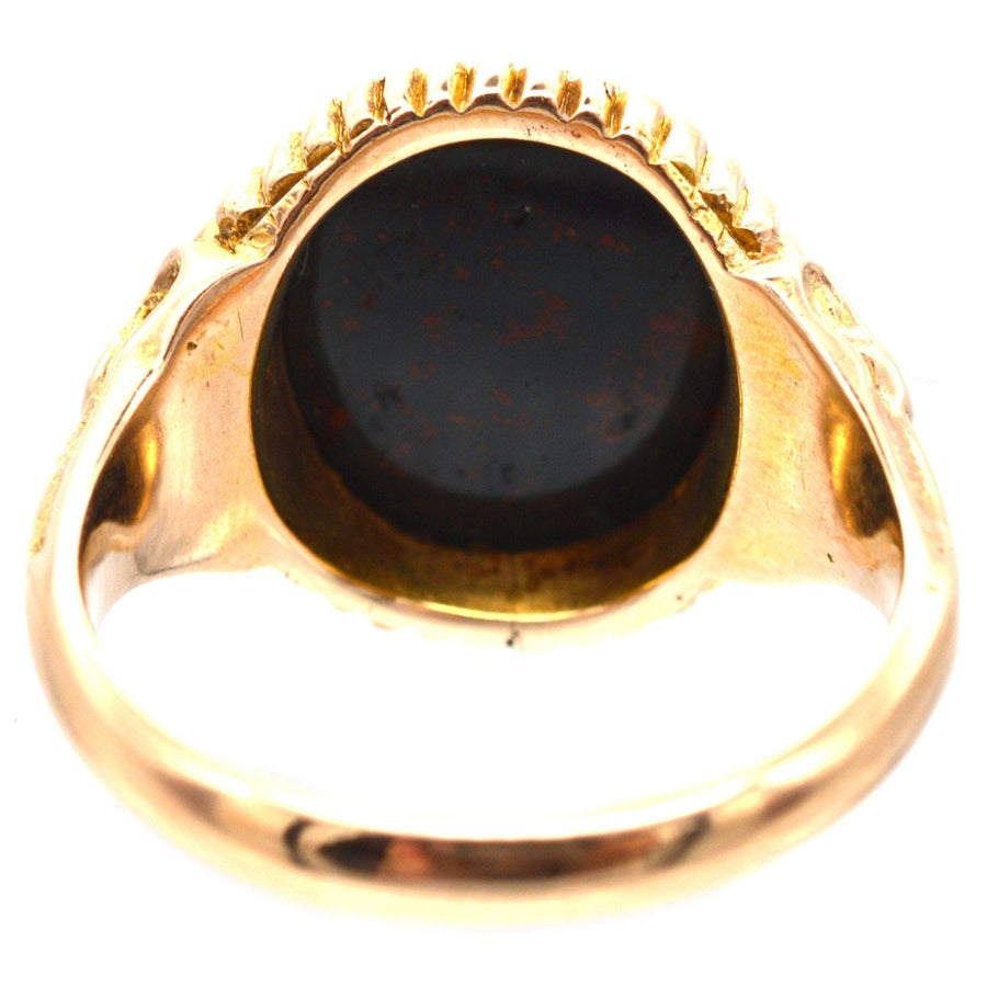 Victorian 15ct gold signet ring featuring an engraved bloodstone and decorative shoulders, assayed in Birmingham 1866.