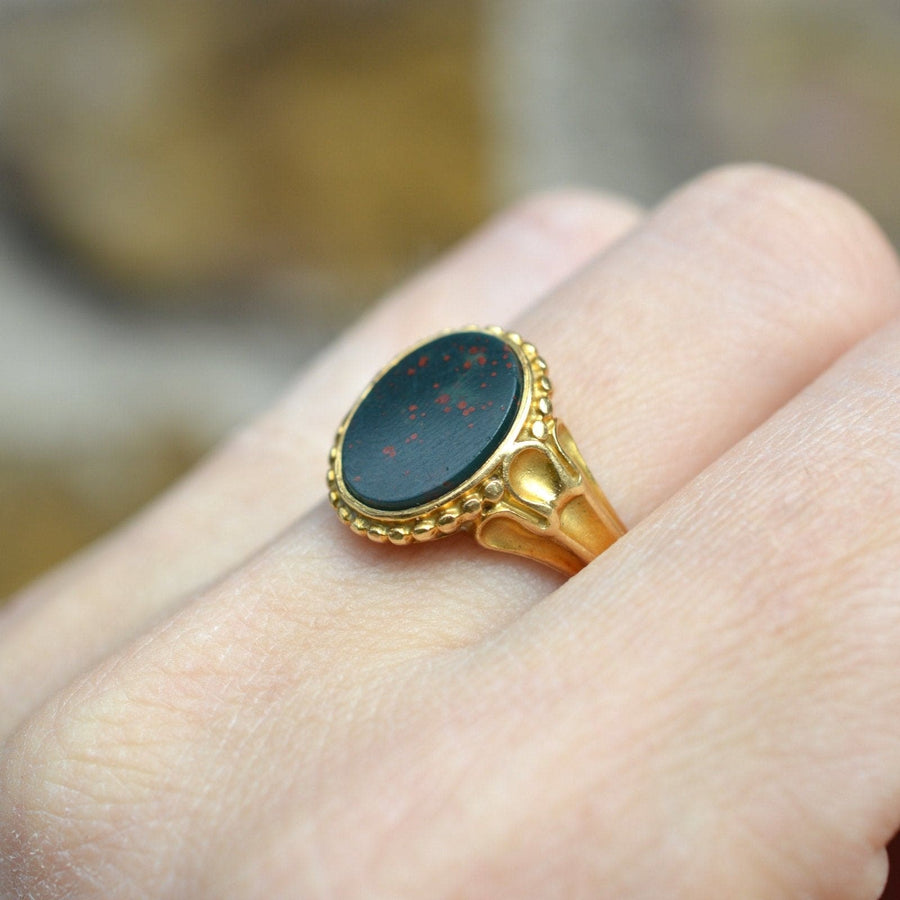 Victorian 18ct gold bloodstone signet ring with decorated shoulders worn on hand.