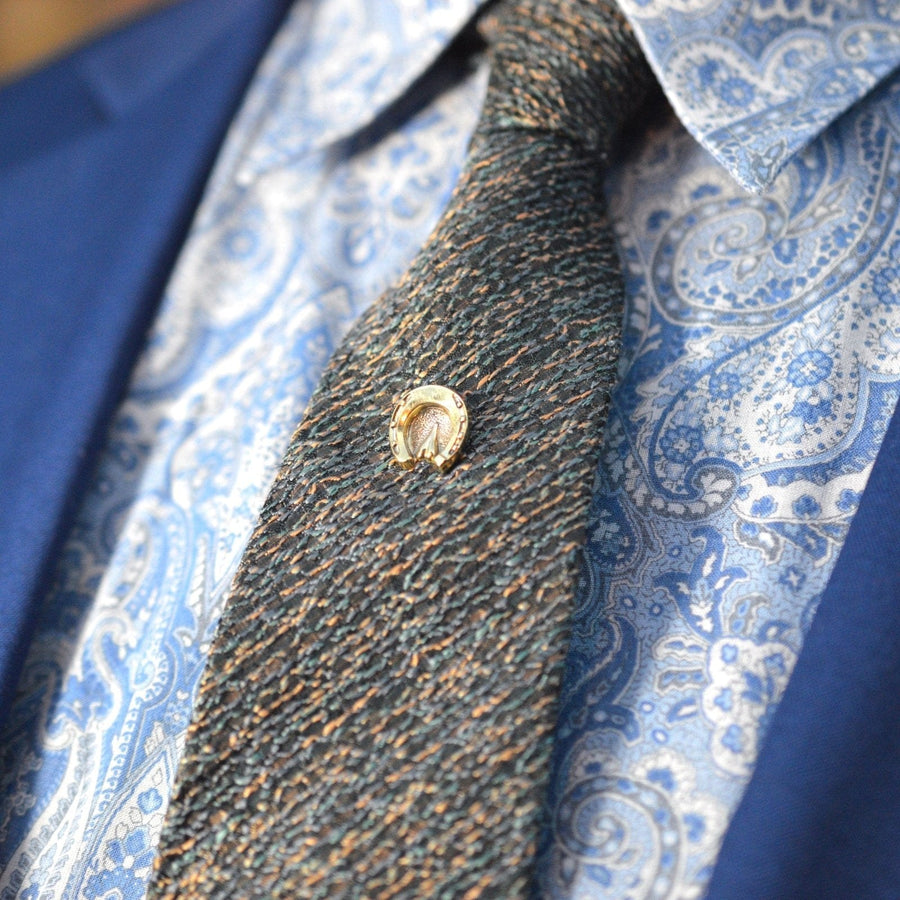 Victorian 9ct gold horseshoe tie pin displayed on a stylish silk tie, symbolizing luck and protection.