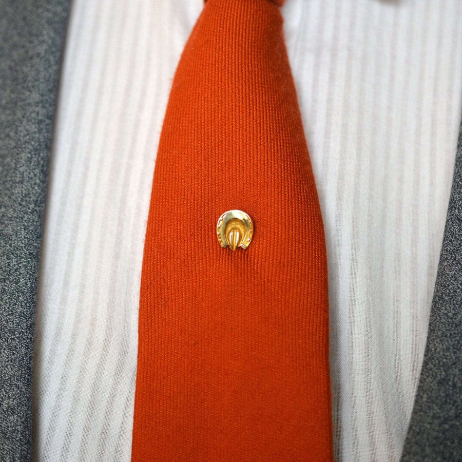 Victorian 9ct gold horseshoe tie pin on a vibrant orange tie, symbolizing good luck and protection.