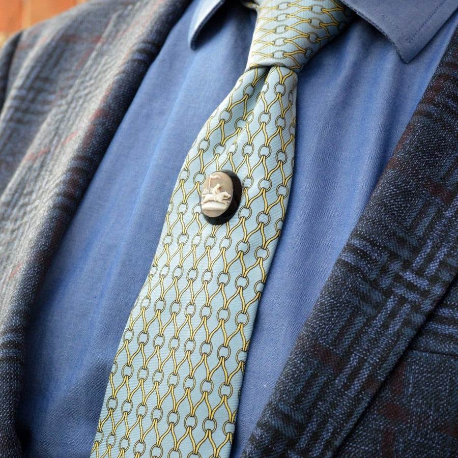 Victorian shell cameo tie pin on a stylish tie with geometric patterns, worn with a checkered blazer.
