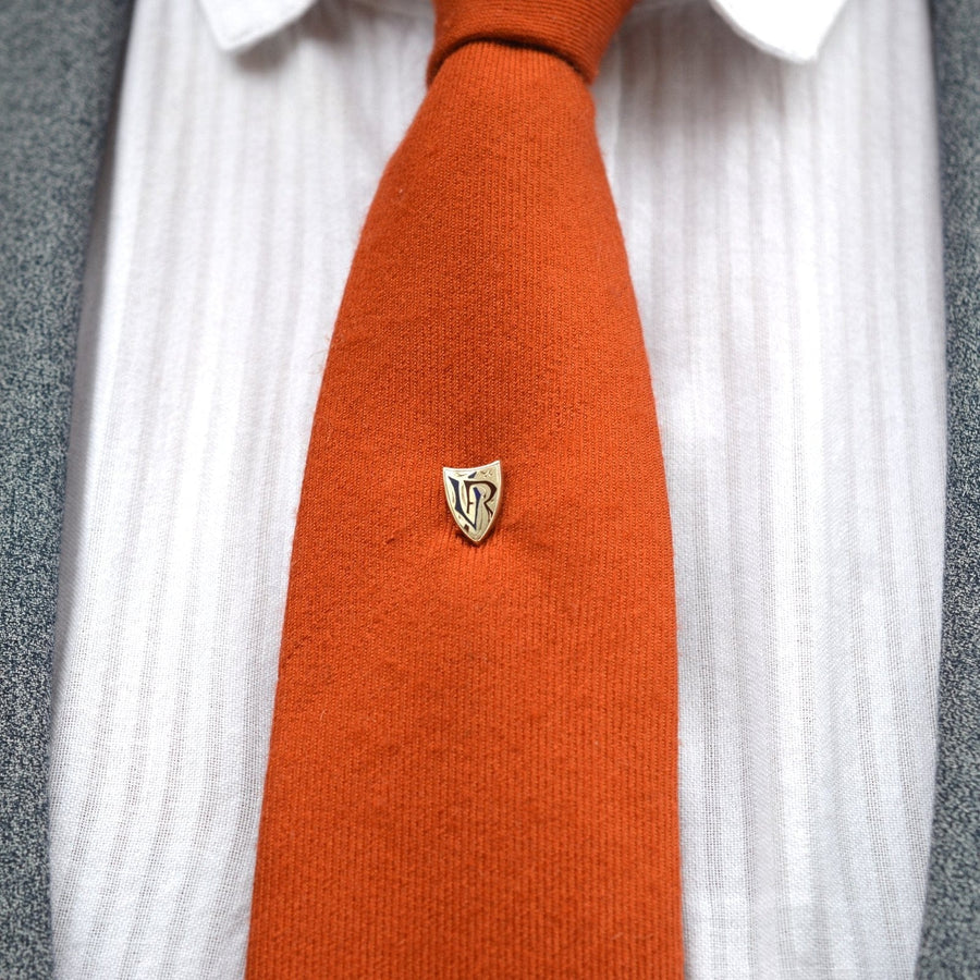 Victorian silver and enamel "Victoria Regina" shield tie pin displayed on an orange tie