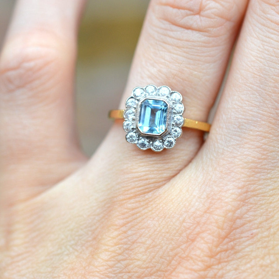 Vintage 18ct gold aquamarine and diamond cluster ring showcased on a hand.
