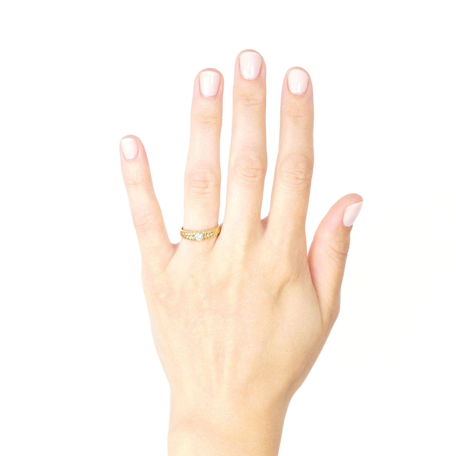 Vintage 18ct gold diamond solitaire ring with laurel wreath shoulders worn on a hand.