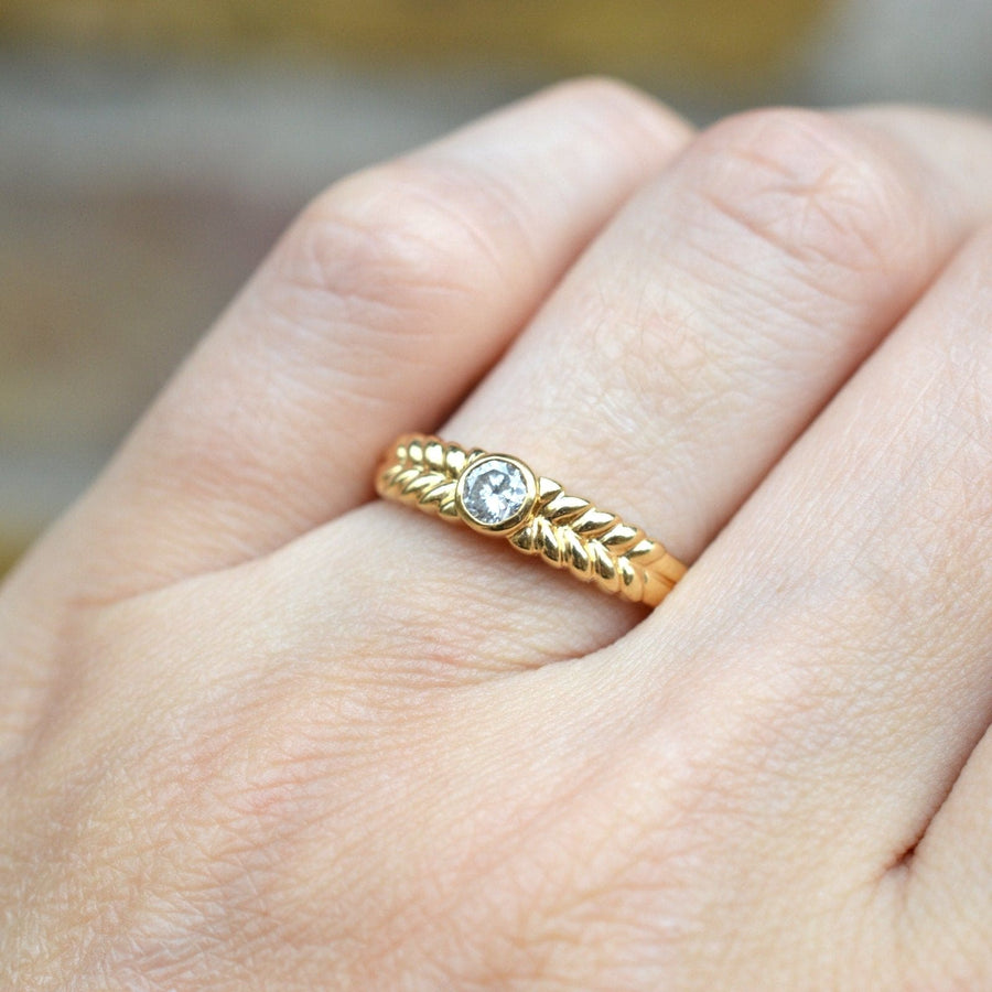 Vintage 18ct gold diamond solitaire ring with laurel wreath shoulders worn on hand.