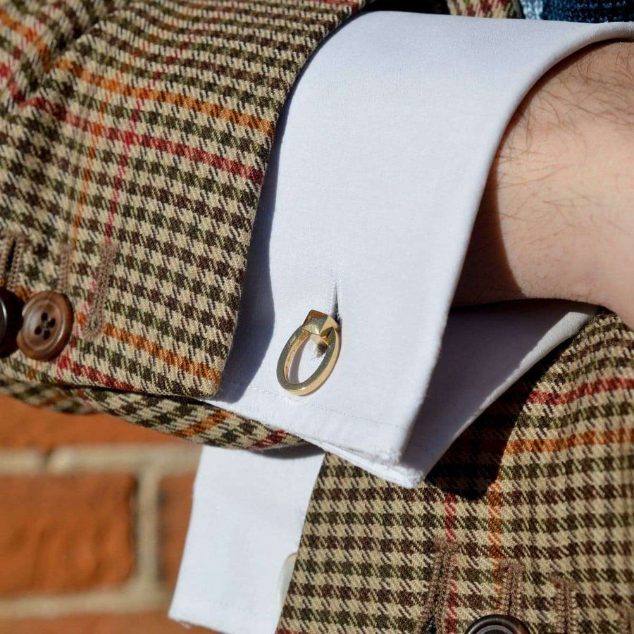 Close-up of vintage 18ct gold cufflinks on a white dress shirt with a patterned blazer.