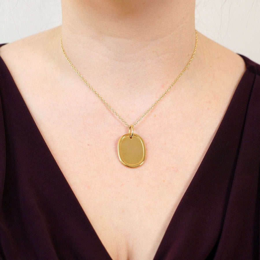 Vintage 18ct gold oval plain name tag pendant worn on a gold chain, perfect for everyday elegance.