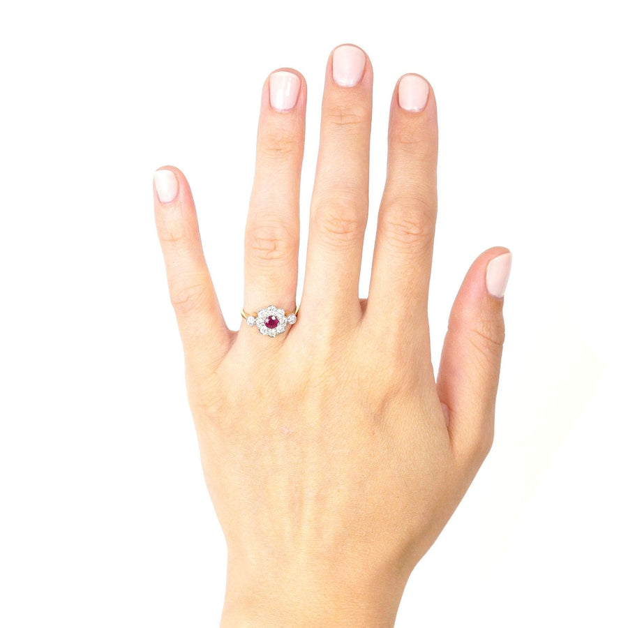Vintage 18ct gold and platinum ruby and diamond cluster ring displayed on a hand.