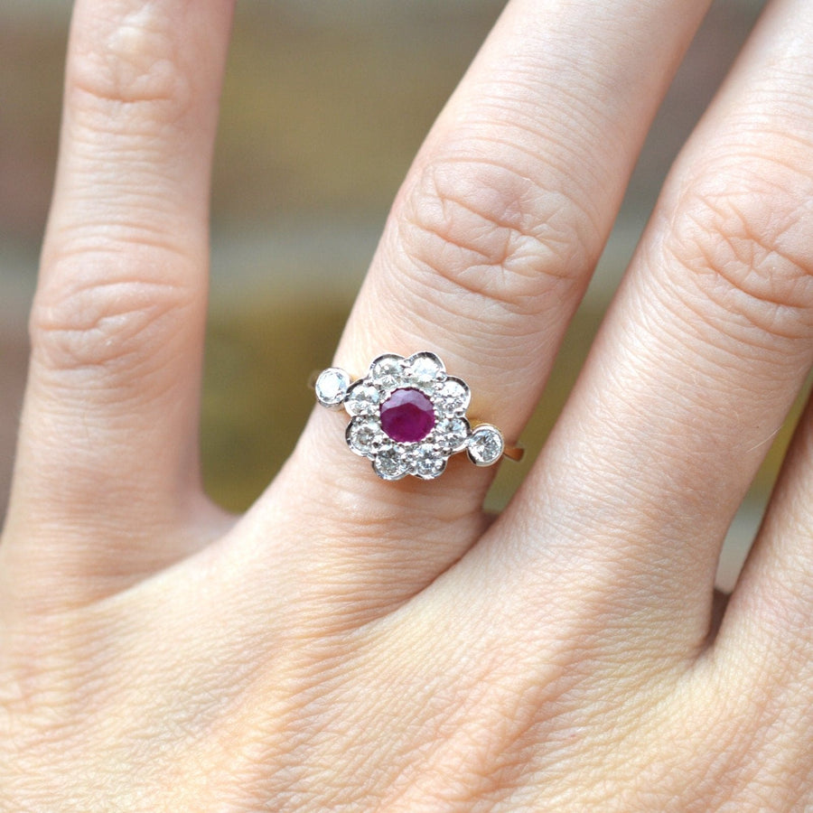 Vintage 18ct gold and platinum ruby and diamond cluster ring on a hand, showcasing a natural ruby centerpiece.