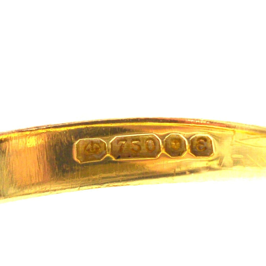 Close-up of 18ct gold hallmark showing 750 purity marks on vintage jewelry.