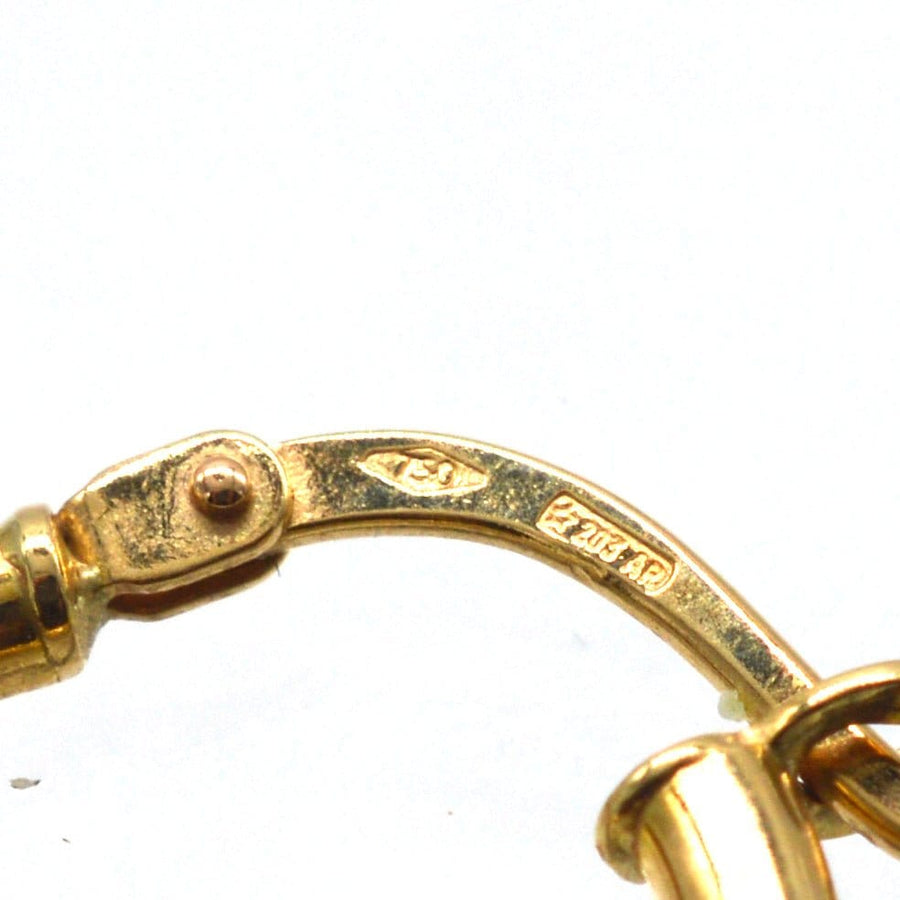Close-up of vintage 18ct gold huggie earring clasp, showcasing intricate details and hallmark.