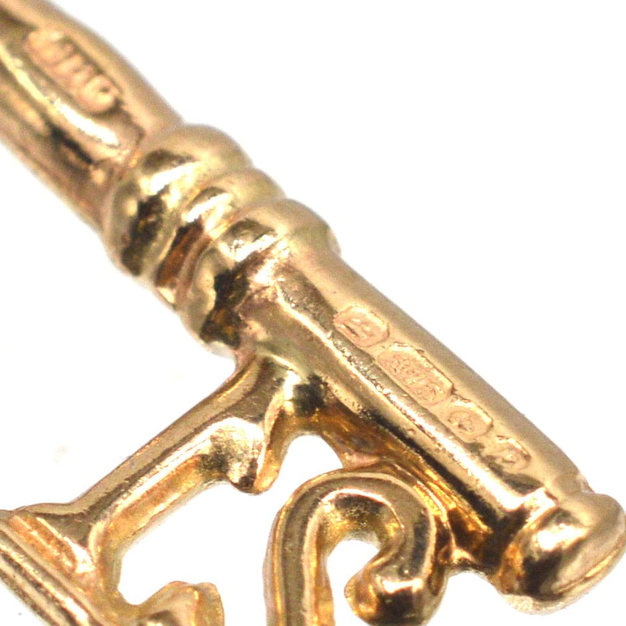 Close-up of a vintage 1970s 9ct gold key charm pendant, featuring detailed engravings and a 21 design.