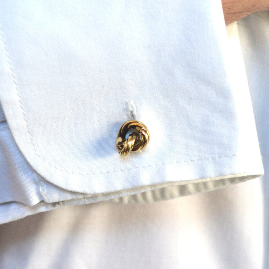 Close-up of a vintage 1990s 18ct gold rope knot cufflink on a white shirt cuff, showcasing intricate design.