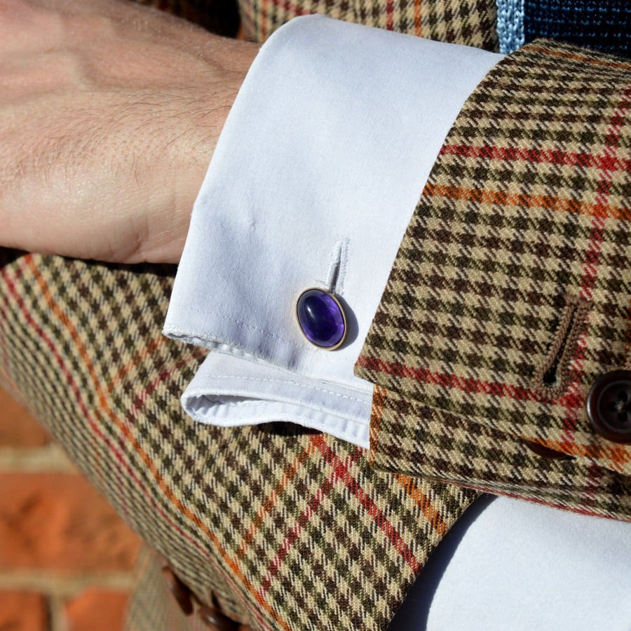 Close-up of vintage 9ct gold amethyst cufflinks on a man's checked shirt cuff.