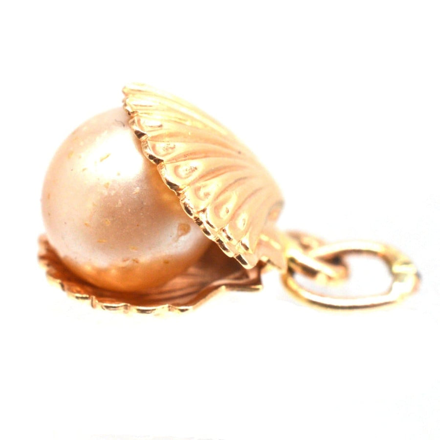 Vintage 9ct gold charm of a scallop shell with imitation pearl, symbolizing strength and hope.