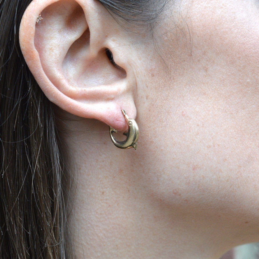Vintage 9ct gold dolphin hoop 'huggie' earrings showcased on a model's ear, symbolizing harmony and elegance.