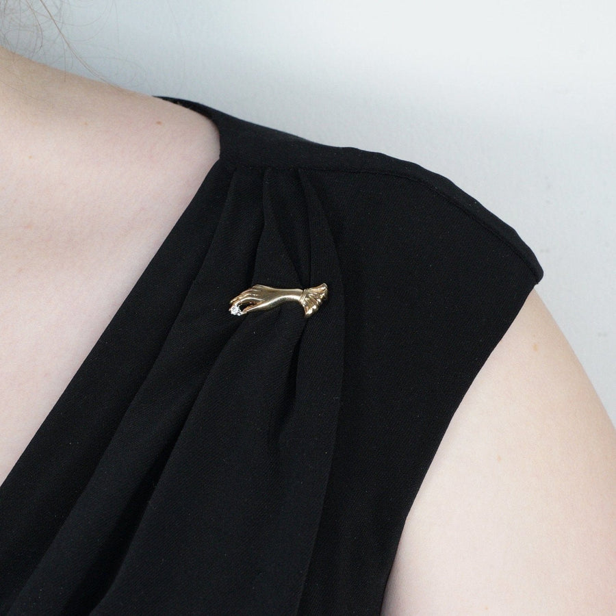Vintage 9ct gold gloved hand brooch with diamond, elegantly worn on a black dress shoulder.