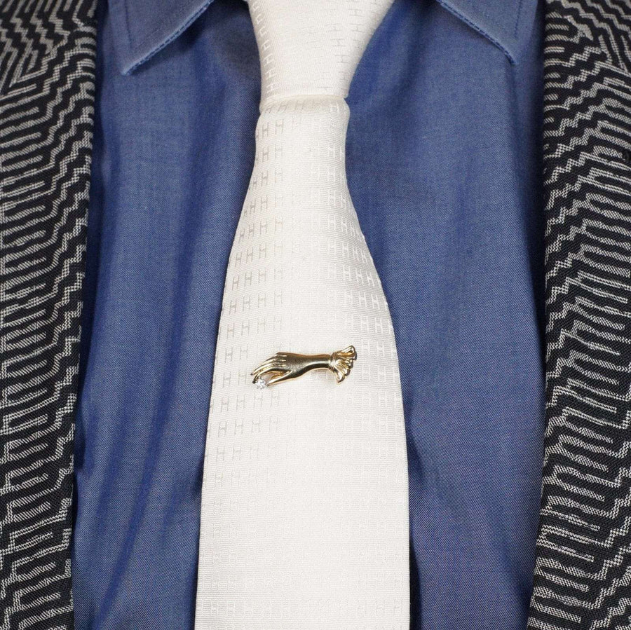 Vintage 9ct gold gloved hand brooch on a white tie, showcasing an elegant fashion statement.