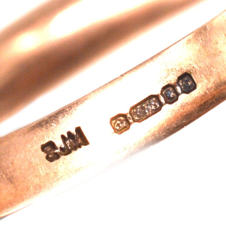 Close-up of vintage 9ct gold Trinity three-colour band ring showing hallmark engravings for authenticity.