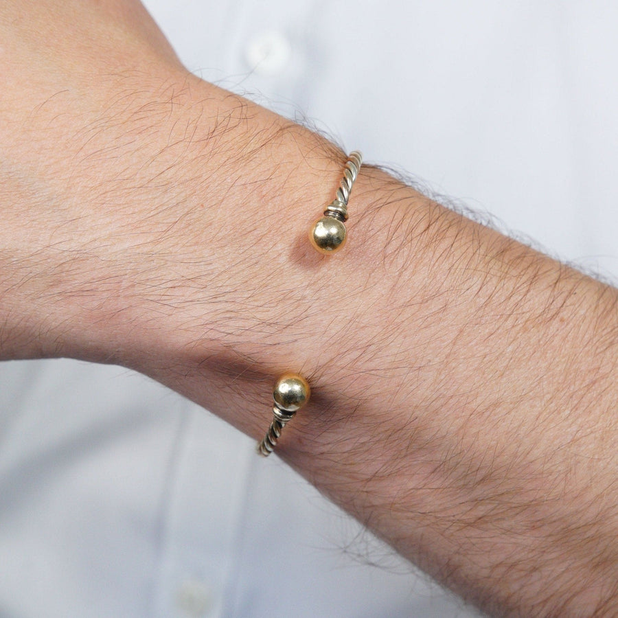 Vintage 9ct gold twisted three colour gold open bangle worn on wrist, showcasing elegant design with gold spheres.