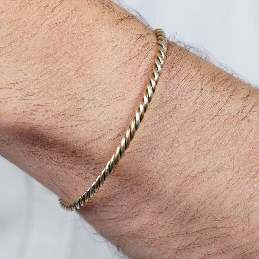 Elegant vintage 9ct gold twisted open bangle with three coloured gold ropes, styled on a wrist.