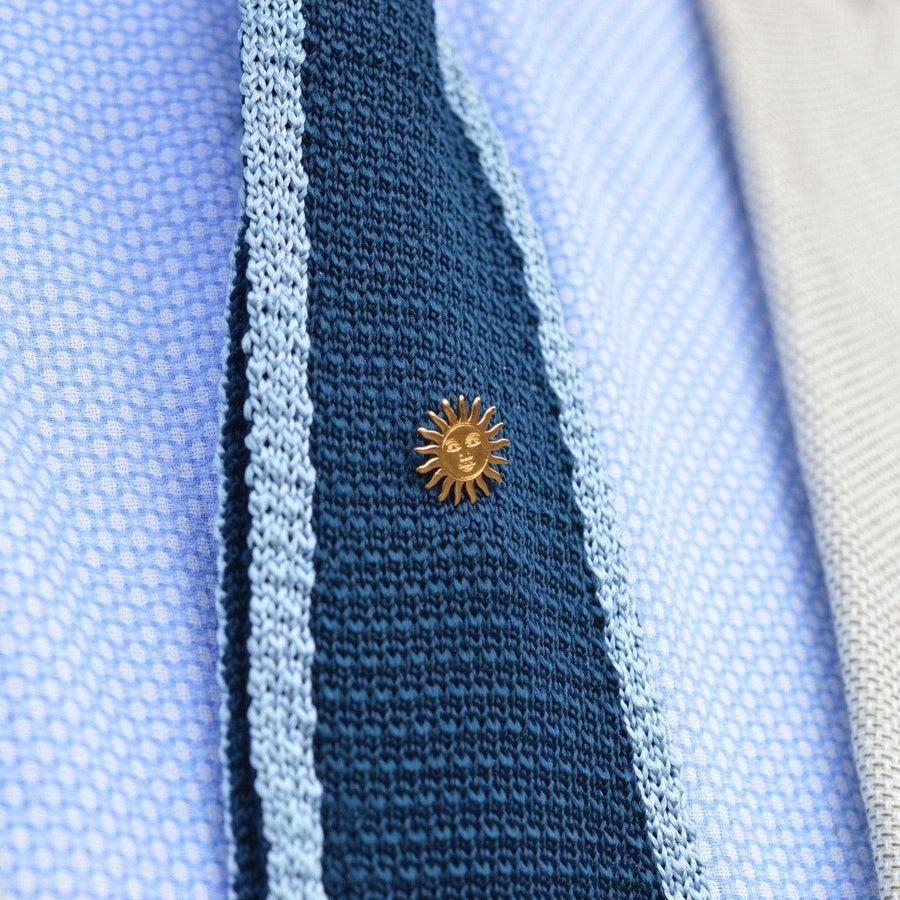 Vintage gold gilt metal sun tie pin on a blue textured tie, adding a touch of elegance and charm.