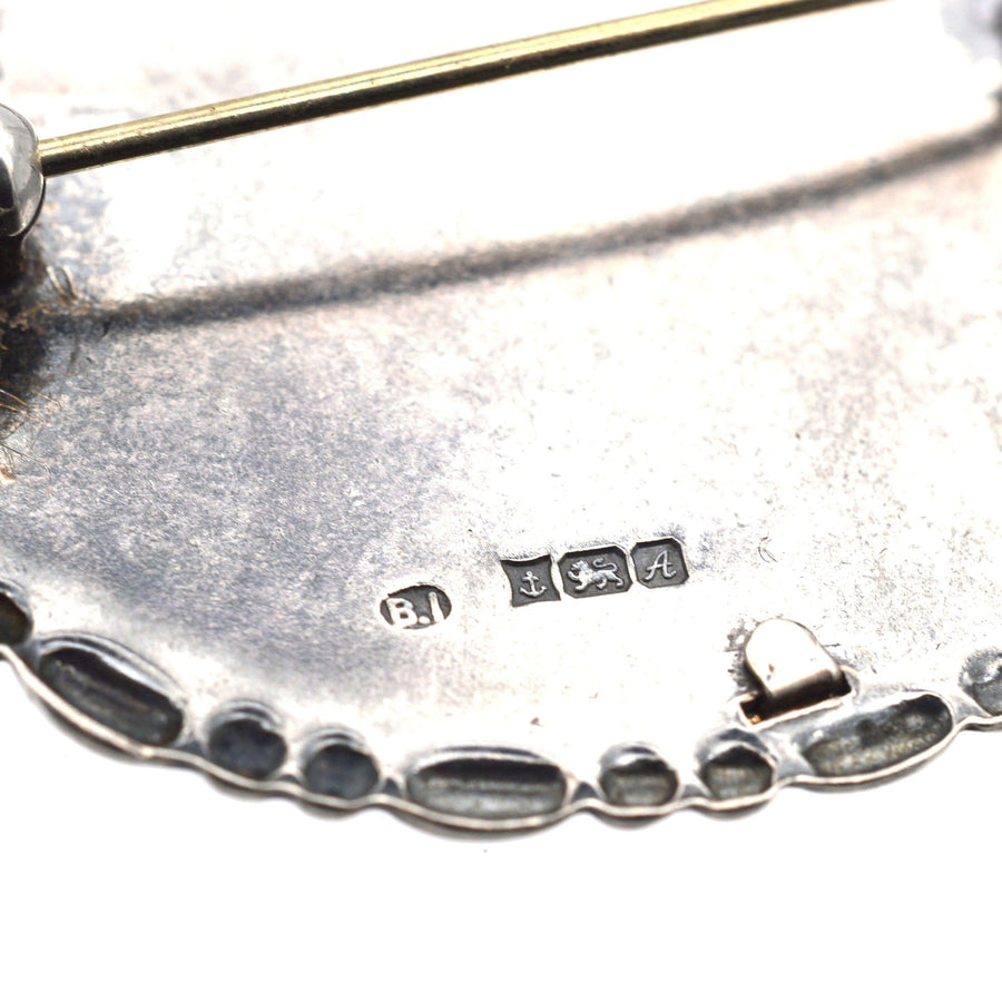 Close-up of vintage silver oval frame brooch back showing Birmingham hallmarks and clasp mechanism.