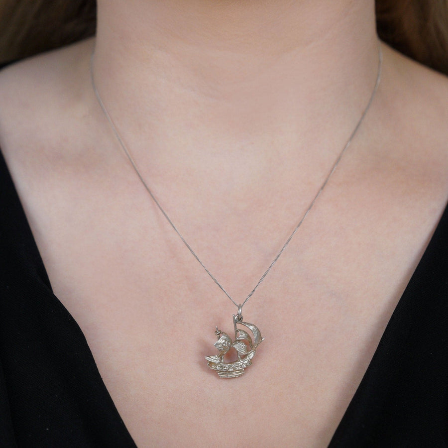 Vintage silver pirate ship pendant with skull sail, stylish necklace worn on a model's neck.