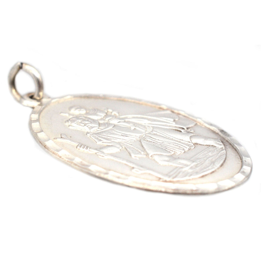 Vintage silver Saint Christopher oval pendant, depicting the saint carrying a child, patron of travelers, circa 1970s.