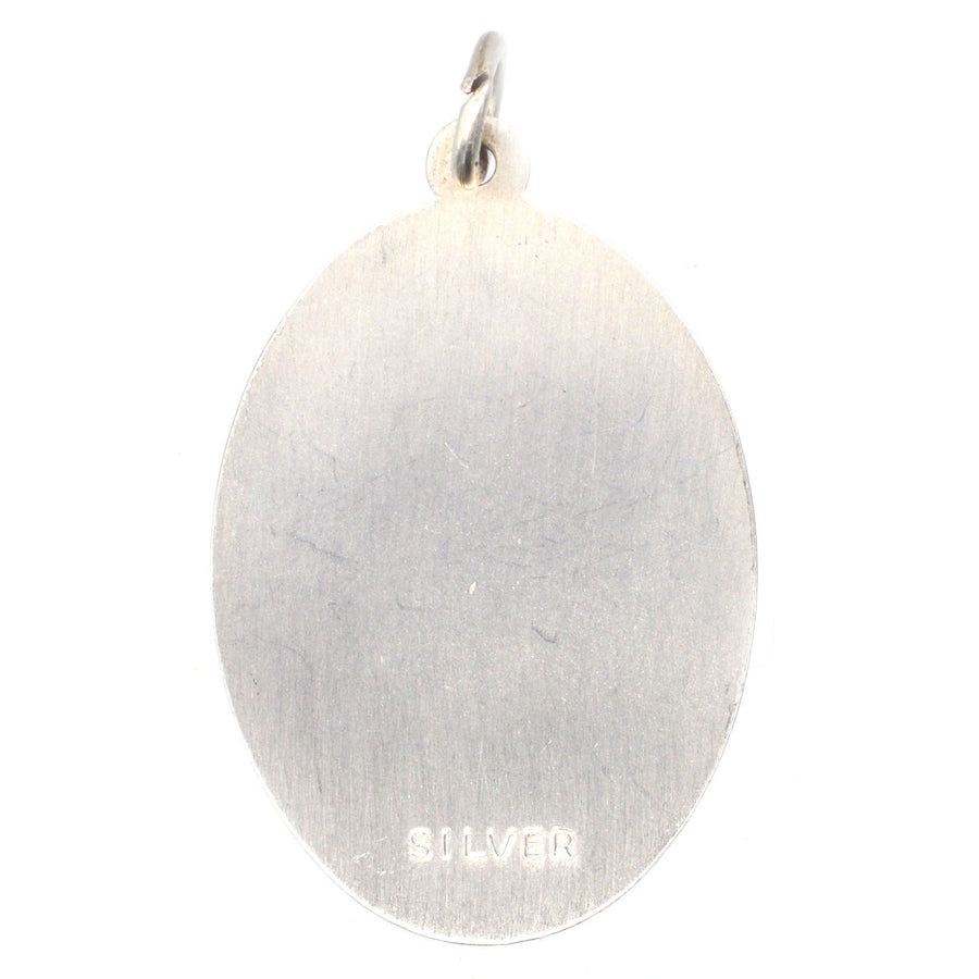 Vintage silver oval pendant featuring Saint Christopher, circa 1970s, with smooth polished surface.