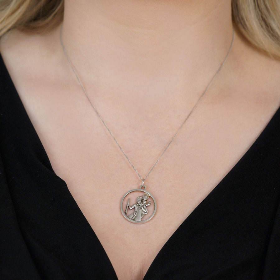 Vintage silver Saint Christopher round pendant worn on a delicate necklace, showcasing the patron saint of travelers.