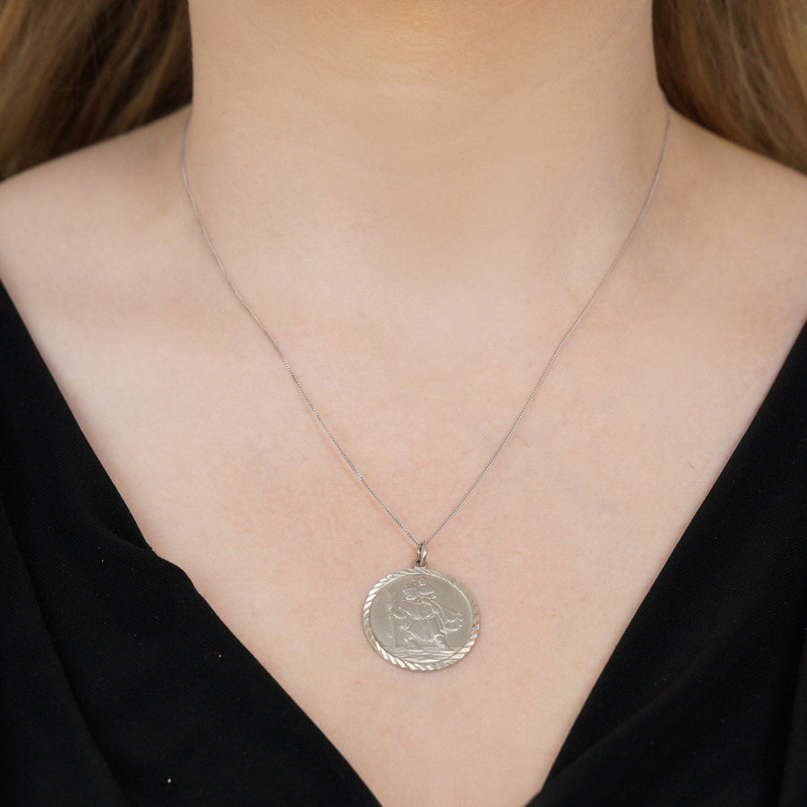 Vintage silver Saint Christopher round pendant worn on a chain, symbolizing protection for travelers.