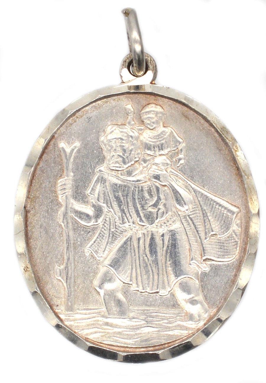 Vintage silver St Christopher pendant depicting the patron saint of travelers carrying a child, circa 1970s.