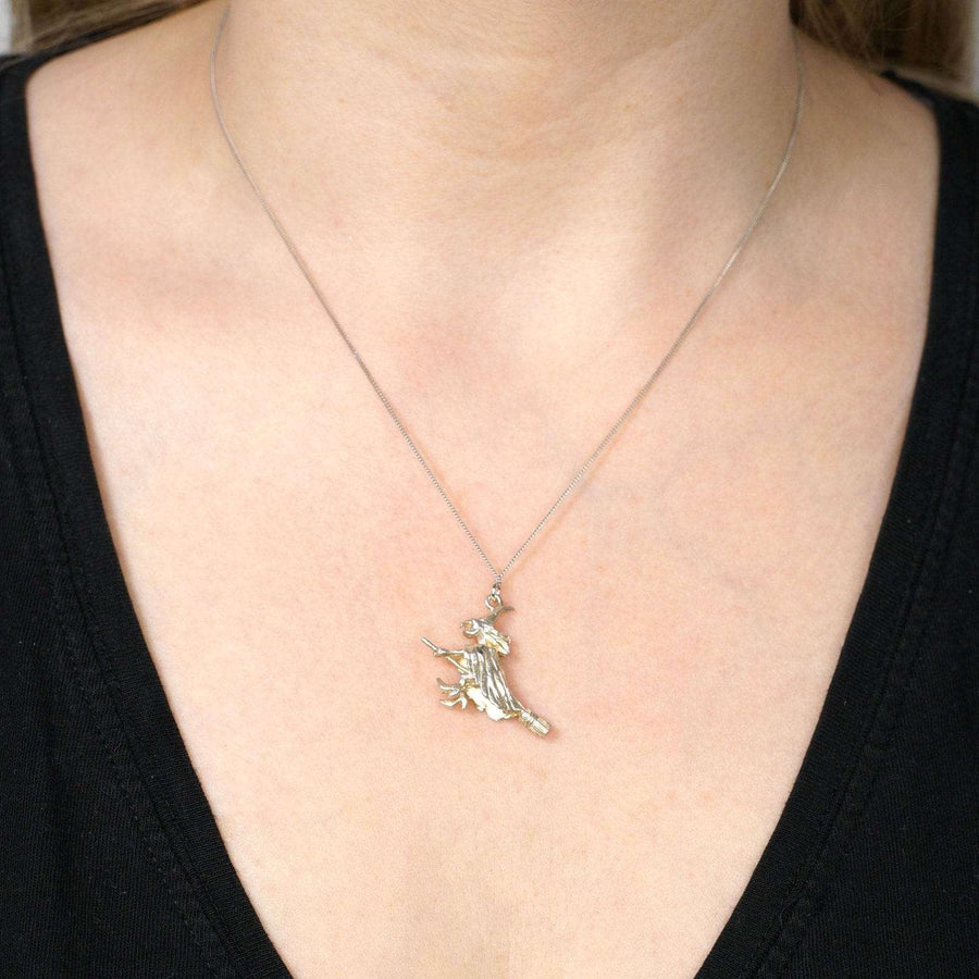 Vintage silver witch on broomstick pendant worn as a charming necklace, ideal for Halloween or whimsical gifts.