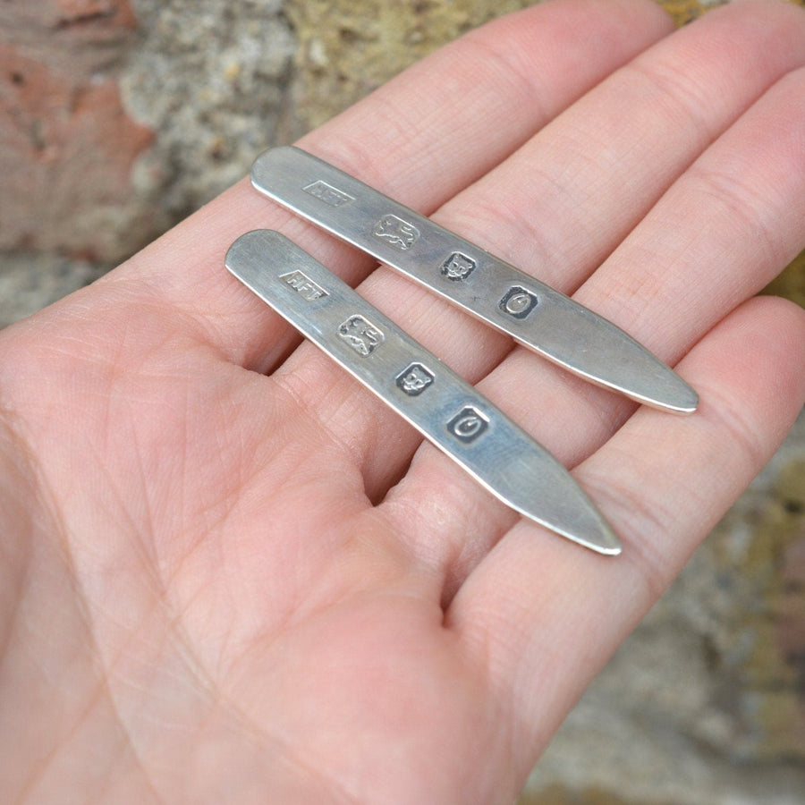Vintage sterling silver shirt collar stiffeners held in hand, showcasing classic design and intricate detailing.