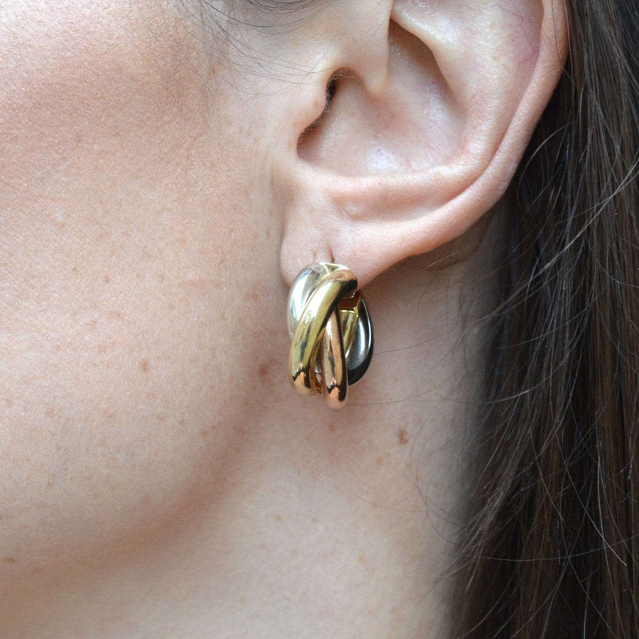Close-up of vintage three colour 9ct gold large open 'Russian Trinity' hoop earrings on a woman's ear.
