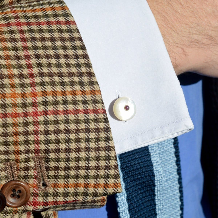 Vintage cufflinks featuring mother of pearl and ruby on a stylish plaid shirt cuff.